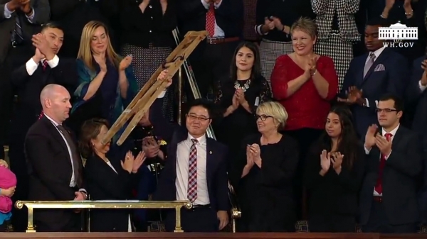 ▲트럼프 대통령의 소개로 자리에서 일어나 자신의 목발을 들어 보이고 있는 지성호 씨 ⓒ백악관 유튜브 영상 캡쳐