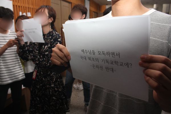 ▲은하선 강연 당시 반대 시위를 하는 한 학생이 “예수님을 모독하면서 국내 최초의 기독교 대학에?”라고 적힌 종이를 들고 있다