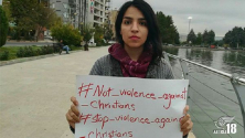 마리아 파티메 무함마디가 “기독교인들에 대한 폭력에 반대한다”는 내용이 적힌 종이를 들고 있다.
