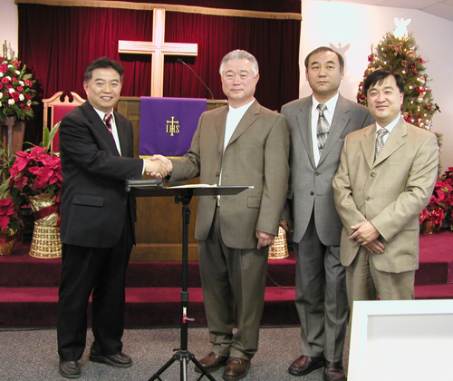 신임회장 박승로 목사와 김성구 회장의 악수, 그외 다른 임원들.