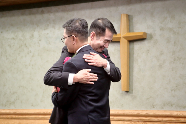은퇴하는 김현수 목사가 위임하는 이승혁 목사를 안아주며 격려하고 있다