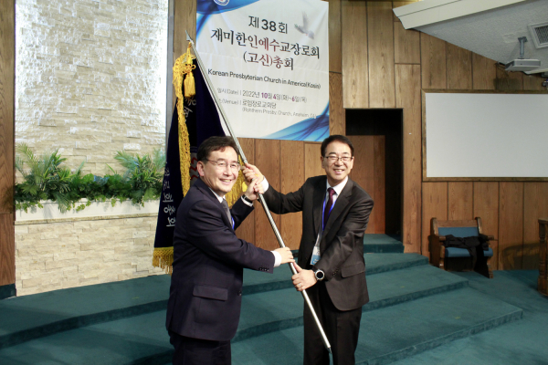 직전 총회장 정지호 목사(오른쪽)가 신임 총회장 한태일 목사(왼쪽)에게 총회기를 전달하고 있다