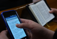 한 교회에서 스마트폰으로 성경을 검색하는 성도와 성경책을 읽는 성도의 모습.