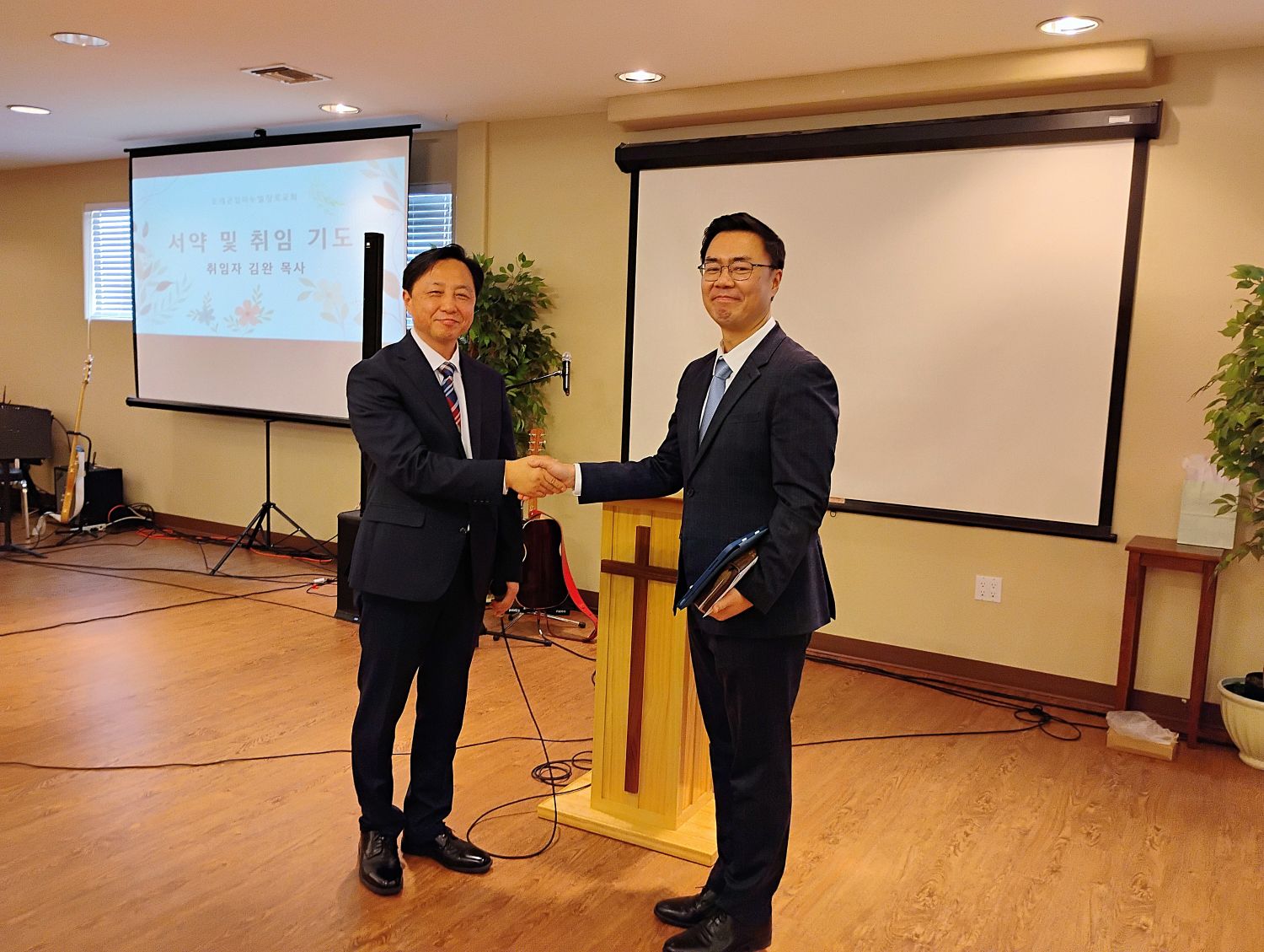 오레곤임마누엘장로교회 제6대 담임으로 취임한 김완 목사(오른쪽)가 제5대 담임 김대성 목사와 취임식에서 악수하고 있다.