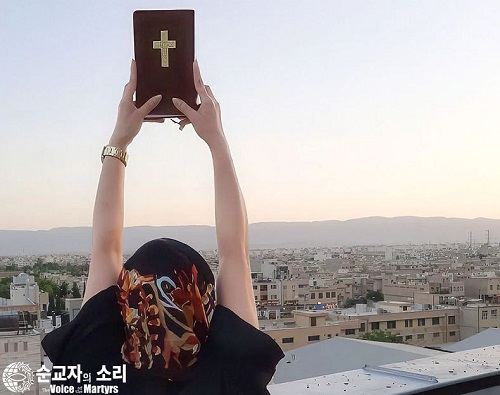 ▲이란의 한 기독교인이 두 손 높이 성경을 들고 도시를 내려다 보고 있다.