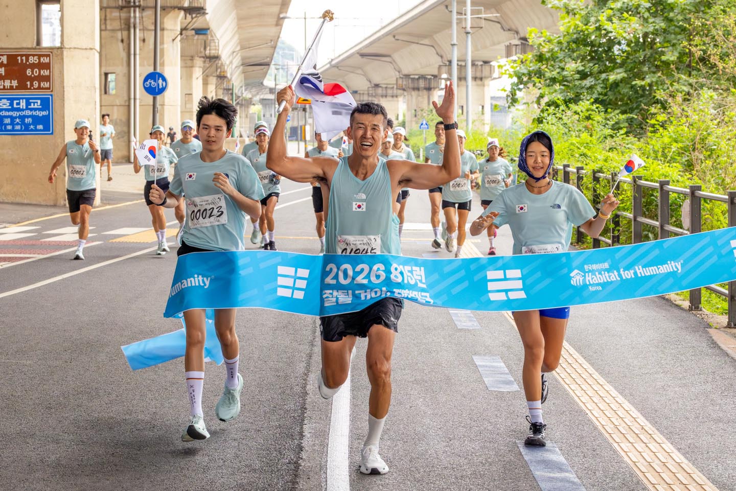 ▲페이서들과 7번째 81.5km 완주에 성공한 가수 션 씨가 아들·딸과 함께 피니시 라인을 통과하고 있다. ⓒ한국해비타트