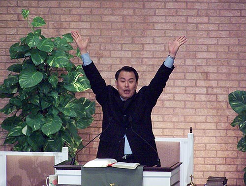 두 손 높이 들고 찬양을 부르는 김기동 전도사