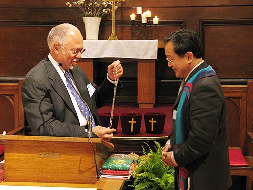 뉴욕 전 노회장(좌)이 노회장 상징물인 십자가 목걸이를 신임 노회장에게 전달하고 있다.