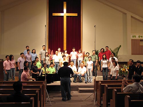 부부들이 색상을 맞춰 옷을 입고 합창하는 모습이다 