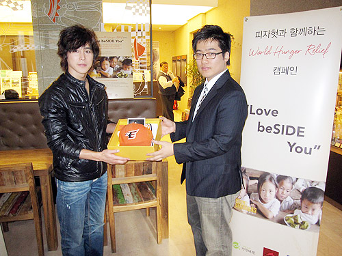 정태우 씨(왼쪽)가 대학로 한 카페에서 서영훈 씨에게 낙찰 애장품인 상의와 모자를 전달하고 있다. ⓒ기아대책 제공