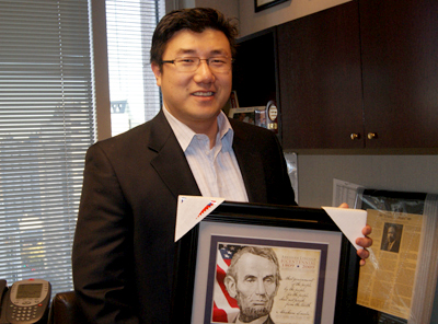 링컨 대통령 사진을 들고 자신의 사무실에 서있는 BJ Pak 의원