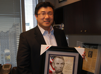 링컨 대통령 사진을 들고 자신의 사무실에 서있는 BJ Pak 의원.