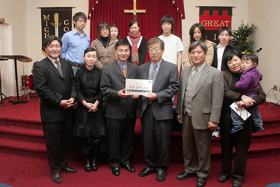 배인덕 운영위원장(왼쪽 세번째)이 정주성담임목사(오른쪽 두번째)와 성도들에게 월드비전 선교동역교회 현판을 증정하고 있다. ⓒ 이화영 기자 
