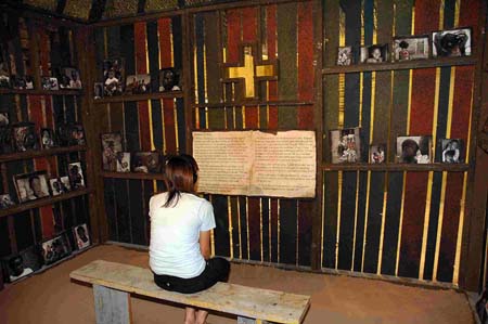 AIDS 체험관을 찾은 한 방문객이 AIDS 사망자들의 사진이 걸려 있는 채플에서 기도하고 있다 