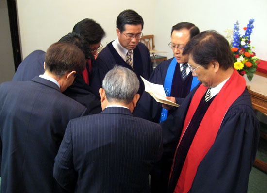 예배에 참여한 목사들과 노회장이 안수받는 고 전도사에게 기도하고 있다.