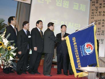 제 30회기 임원진이 신임 임원진들에게 교협 깃발을 인수인계하고 있다.