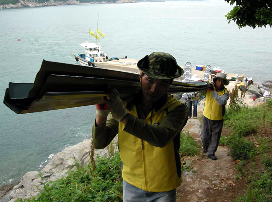 수항도의 이도옥 할아버지와 황본자 할머니 집의 수리를 위해  봉사단들이 건축 자재들을 나르고 있다.