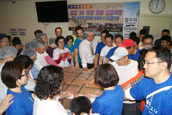 북한어린이돕기 위한 사랑의 영양쌀 포장을 모두 마치고 김재열 목사를 비롯한 자원봉사자들이 쌀포장에 손을 얹고 기도하고 있다.