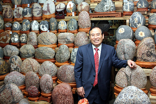 박병선 집사가 자신이 모은 수석들 앞에서 환하게 웃고 있다. 박 집사 뒤로 십자가 모양이 그려진 수석 등 다양한 수석들이 눈에 띈다. ⓒ김진영 기자