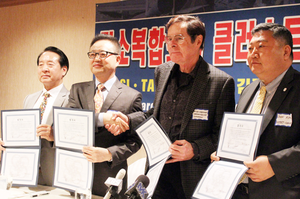 이 계약에 서명한 이들과 증인들이 악수하고 있다. (좌측부터) 비즈포스트 사의 김승학 개발담당 회장, 타콤 사의 박중언 대표, 길버트 헤게마이어 박사, 비즈포스트 사의 존 김 회장.