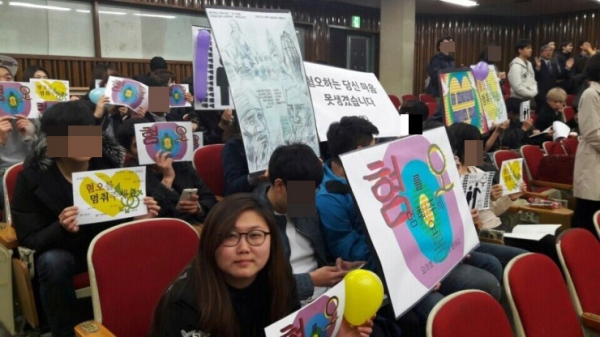 이날 수요열린예배에 QIS 측이 참석해 피켓을 들고 있는 모습. 정면을 바라보고 있는 여성이 김보미 총학생회장이다.