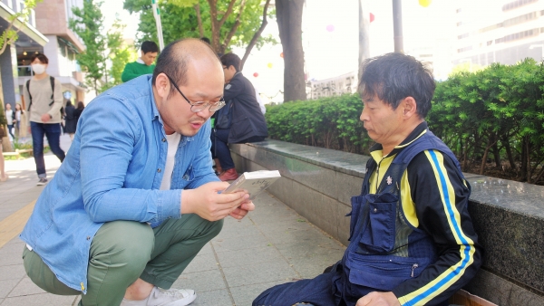 ▲예수 믿는 청년 김건희씨(왼쪽)가 광화문에서 노점을 하며 시를 쓰는 뇌병변장애를 가진 정재완 시인을 만나 대화하고 있다. ©오상아 기자